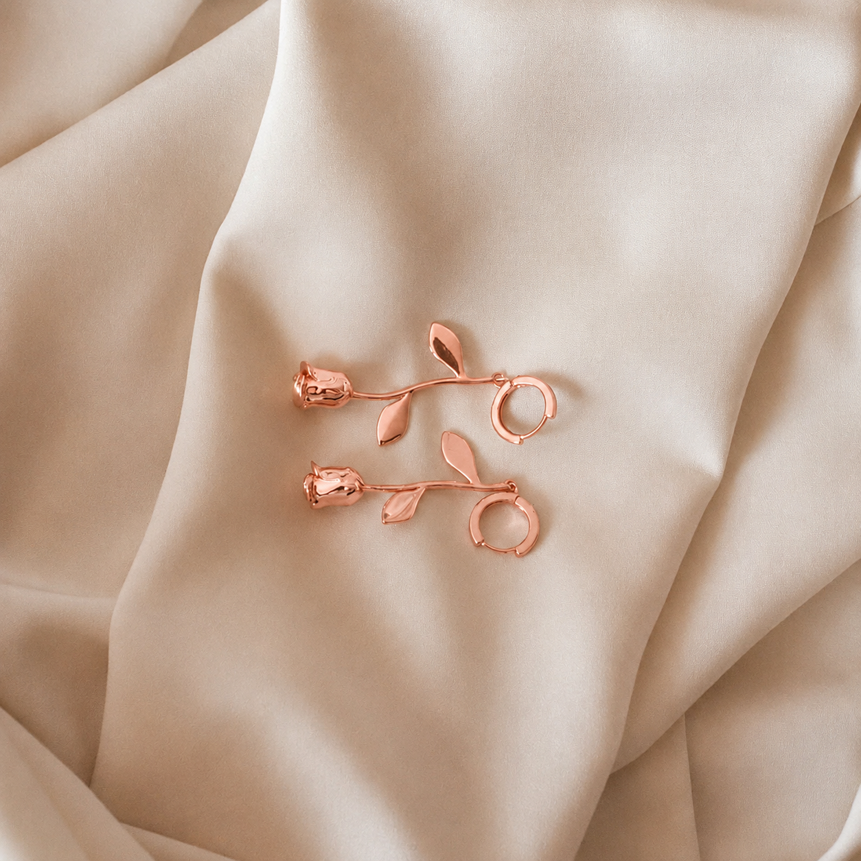 Rose gold floral earrings on beige fabric